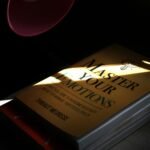 Book titled master your emotions under a lamp.